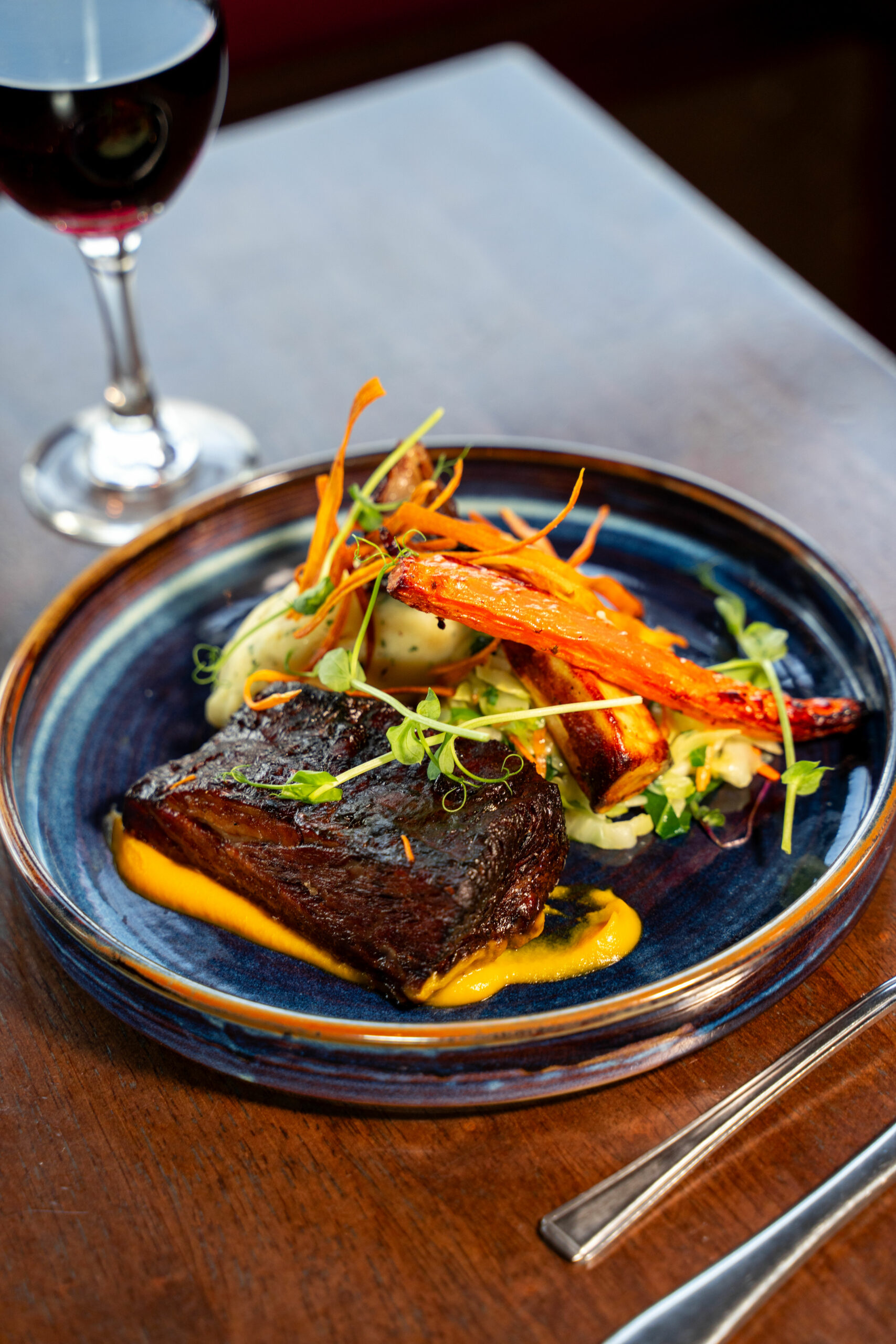 Braised short rib with carrot purée and roasted carrots, served with red wine at an Irish gastro-pub.