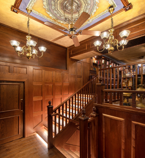 Warmly lit wooden staircase inside The Queen Victoria City Pub